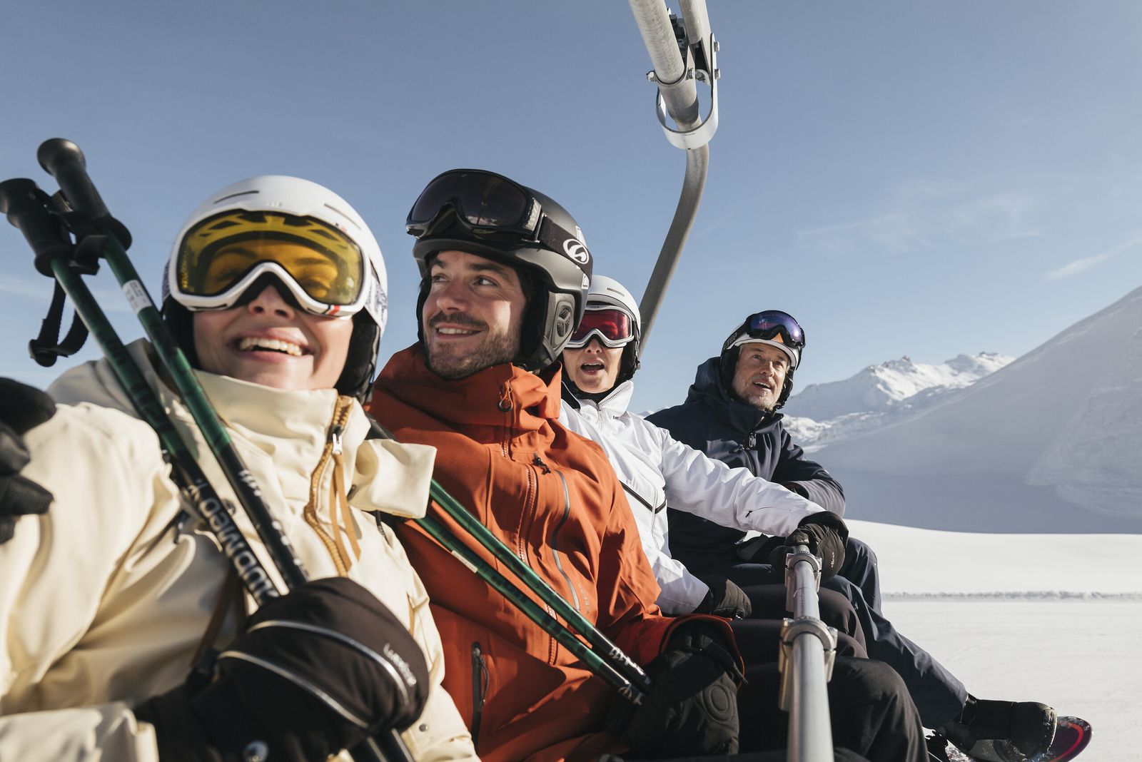 Grupo de amigos sorrindo no teleférico, com esquis