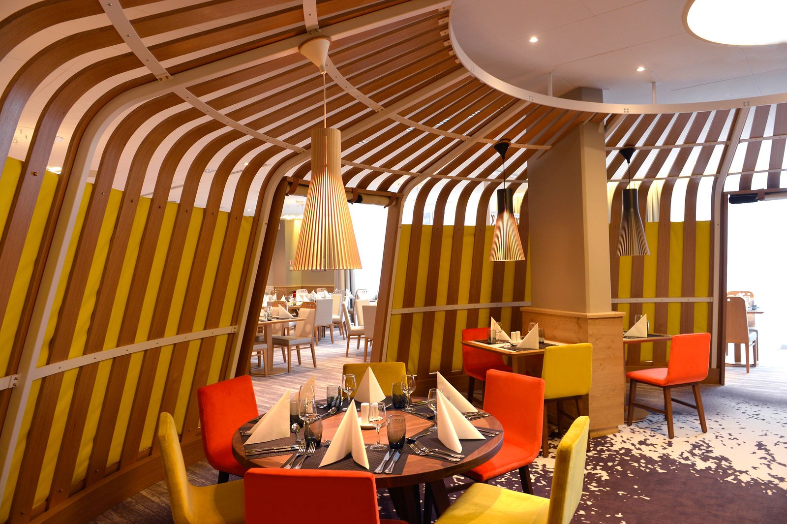 Restaurante com estrutura de madeira curva e cadeiras coloridas