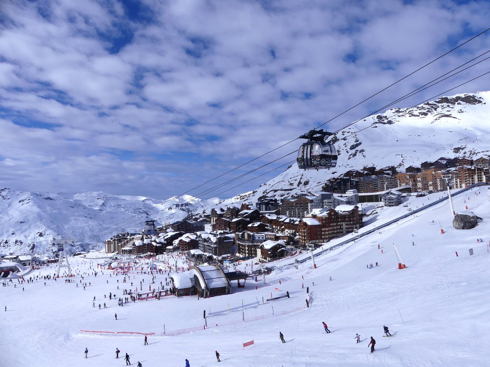 Vila de Val Thorens na neve, com cabos do Funitel e esquiadores na pista